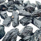 Hand-scale shot of a Black Tourmaline raw stone, sourced from Brazil.