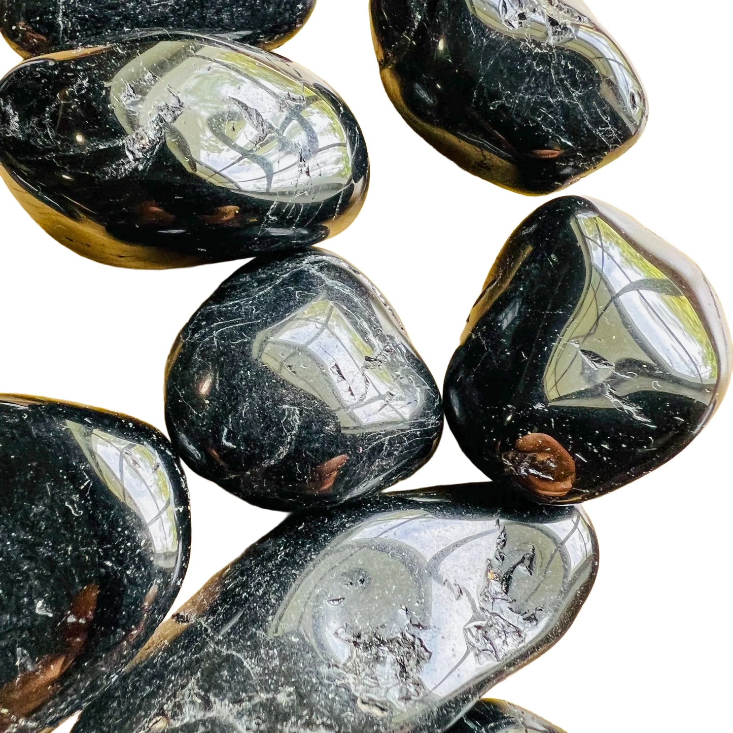 Size comparison with a Black Tourmaline tumbled stone held against natural backdrop.