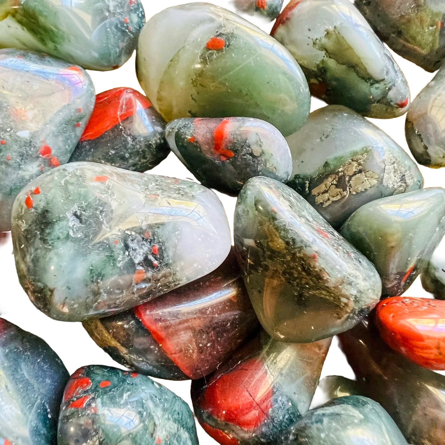 Edge view of Grade AA Bloodstone tumbled stone, showing translucent edges, drawn on for Energy.
