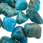 On a soft surface rests an Apatite tumbled stone, from Anosy, Madagascar, traditionally used for Focus, showing the piece in repose.