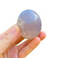 Lateral view of Blue Rose Quartz palm stone, showing natural texture, Madagascar-sourced.