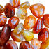 Sideways view of Carnelian tumbled stone, showing natural inclusions, carried for Energy.