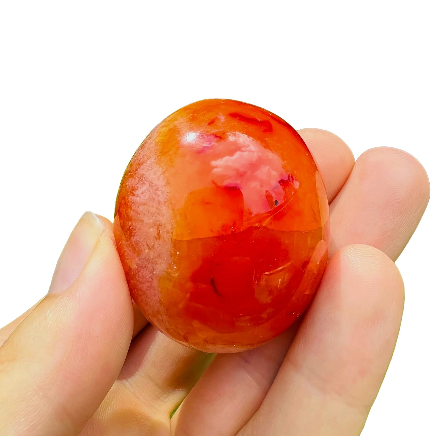 Daylight view of a Carnelian palm stone held against natural backdrop.