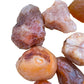Palm-scale view of a Carnelian raw stone held against natural backdrop, from Malawi.