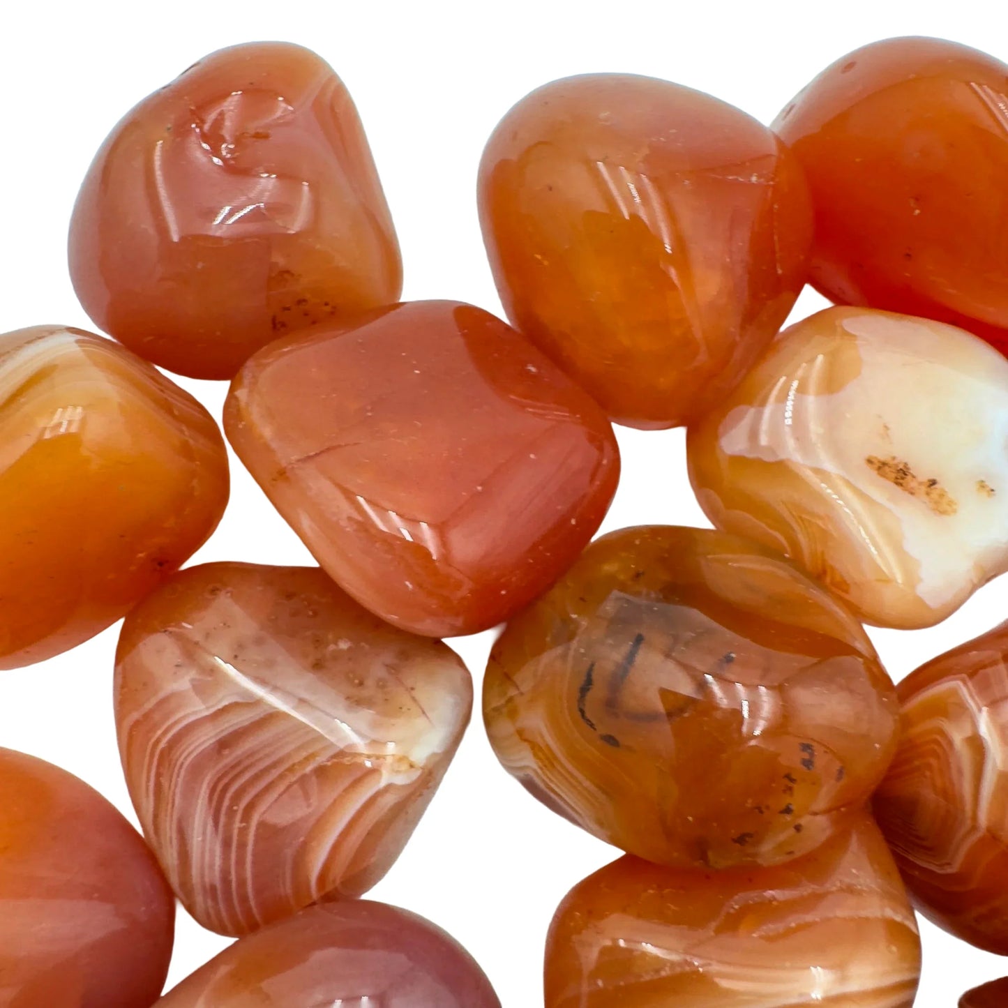 Palm-scale view of a Carnelian tumbled stone held against natural backdrop.