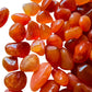 Sideways view of Carnelian tumbled stone, kept near for Energy and Confidence, showing color depth.