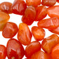 Underside view of Carnelian tumbled stone, showing natural sheen, kept close for Energy.