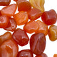 Lifestyle view of a Carnelian tumbled stone held against natural backdrop, hand-selected from Francistown, Botswana.