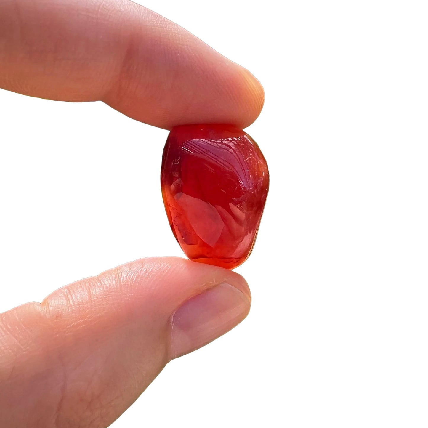 Side-on view of Carnelian tumbled stone, showing translucent edges.