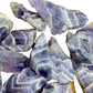 Held in hand, a single Chevron Amethyst raw stone sourced from Zambia.