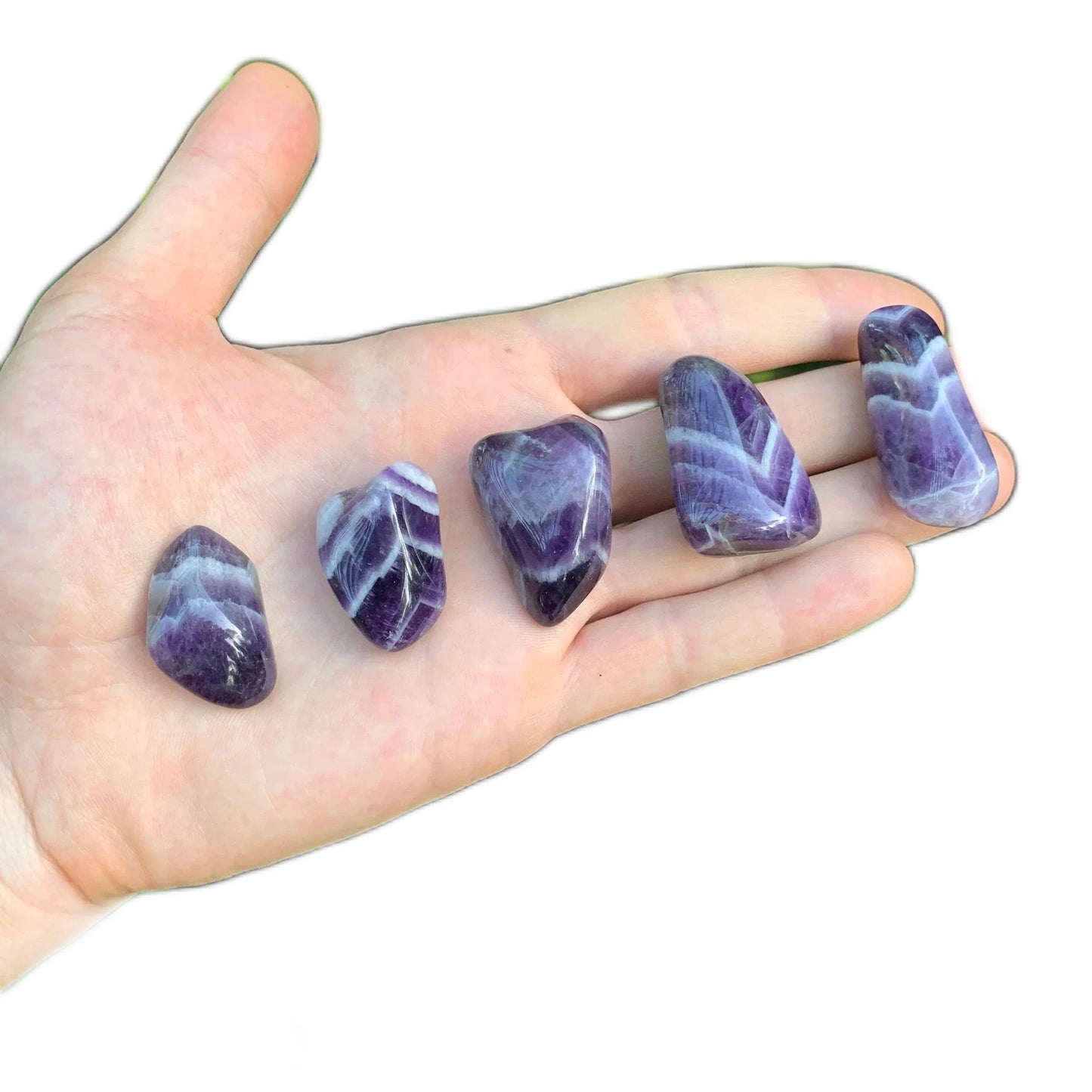 Composed shot of Chevron Amethyst tumbled stone, shown at hand scale.