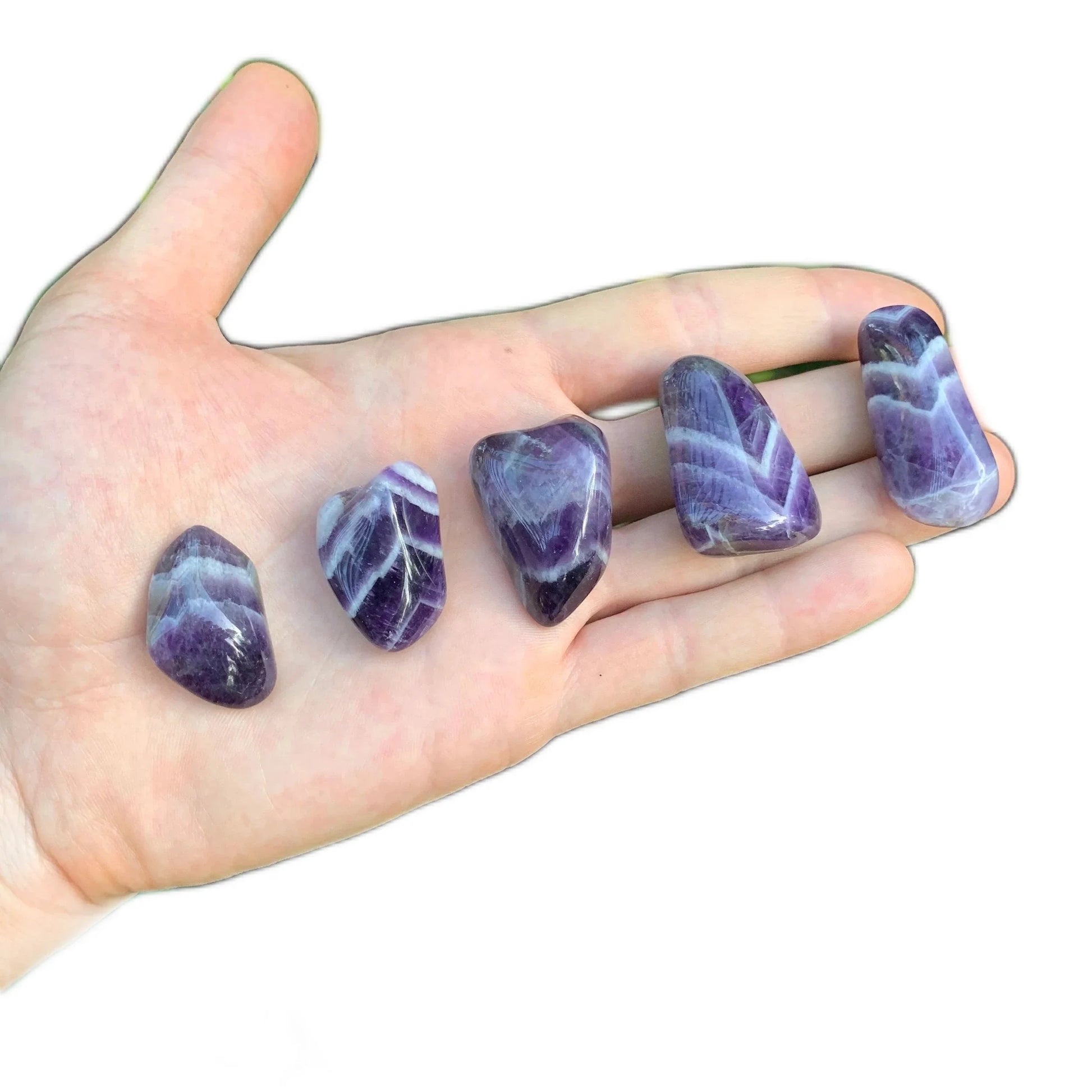 Composed shot of Chevron Amethyst tumbled stone, shown at hand scale.