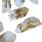 Lifestyle view of a Clear Quartz raw point held against natural backdrop.