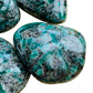 Daylight view of a Emerald palm stone held against natural backdrop.