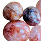 Three-quarter view of Fire Quartz palm stone, captured against a quiet backdrop.