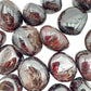 Hand-scale shot of a single Garnet tumbled stone hand-selected from Nsipe, Malawi.