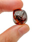 Held in hand, a single Garnet tumbled stone hand-selected from Minas Gerais, Brazil.