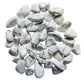 Lifestyle still of Howlite tumbled stone, shown at hand scale.