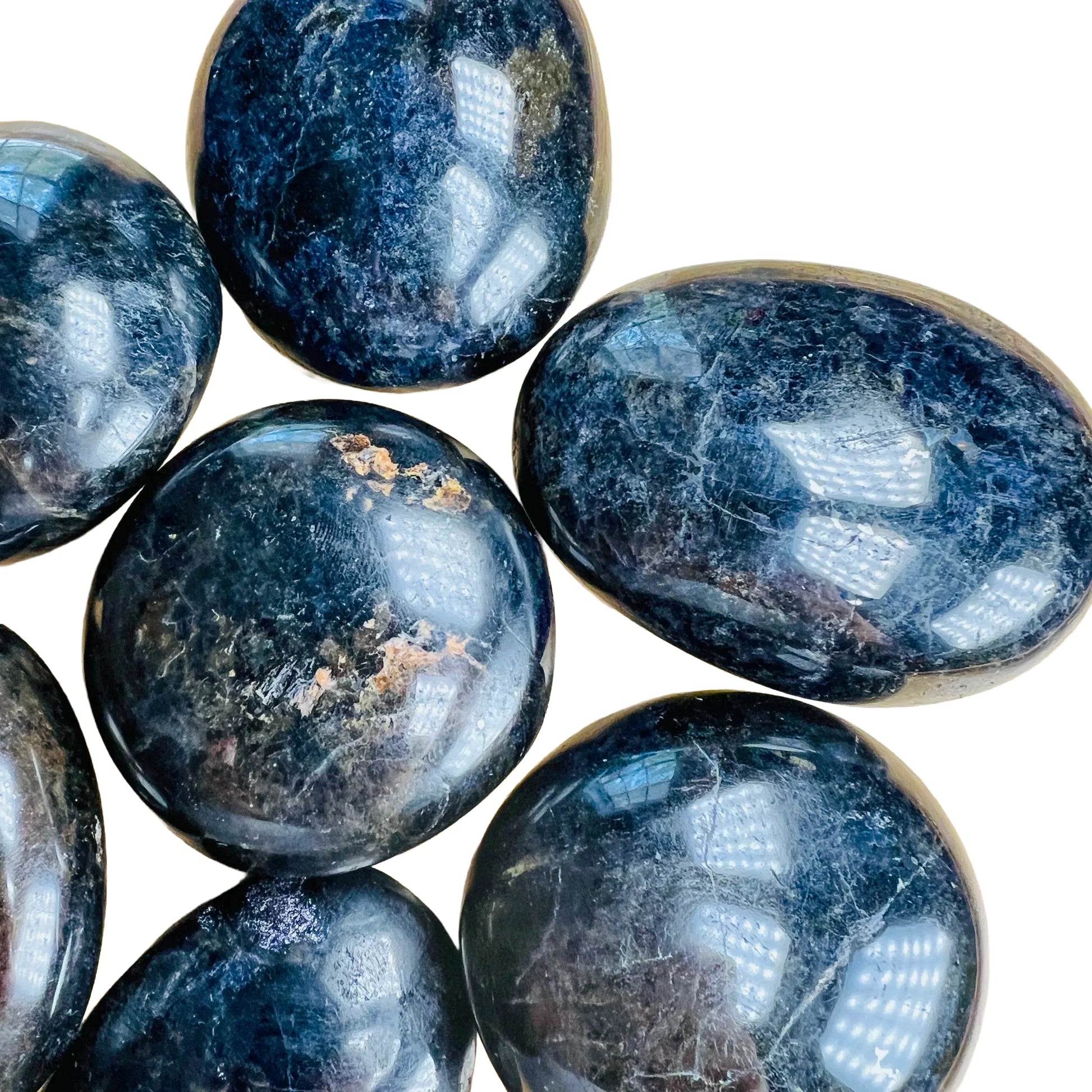 Palm-scale view of a Iolite palm stone held against natural backdrop.