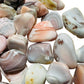 Hand-held view of a Pink Agate tumbled stone often worked with for Love and Self Love, from Botswana.