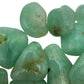 Held in hand, a Prehnite tumbled stone held against natural backdrop.