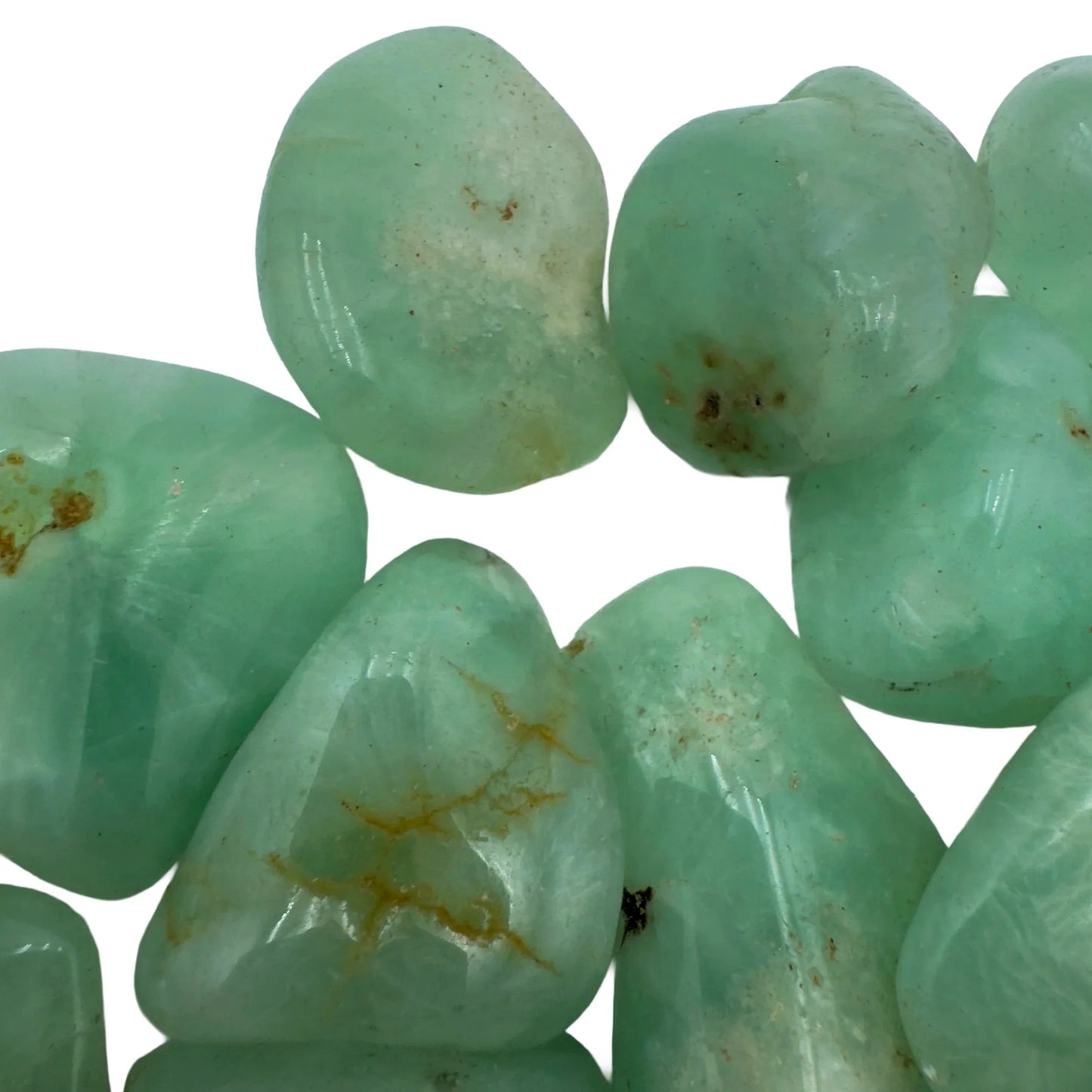 Held in hand, a Prehnite tumbled stone held against natural backdrop.