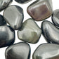Edge view of Rainbow Obsidian tumbled stone, showing color depth.