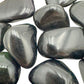 Overhead angle of black Rainbow Obsidian tumbled stone, showing subtle veining.