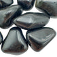 Palm-scale view of a Rainbow Obsidian tumbled stone held against natural backdrop, sourced from Mexico.