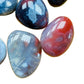 Size comparison with a Red Agate tumbled stone held against natural backdrop.