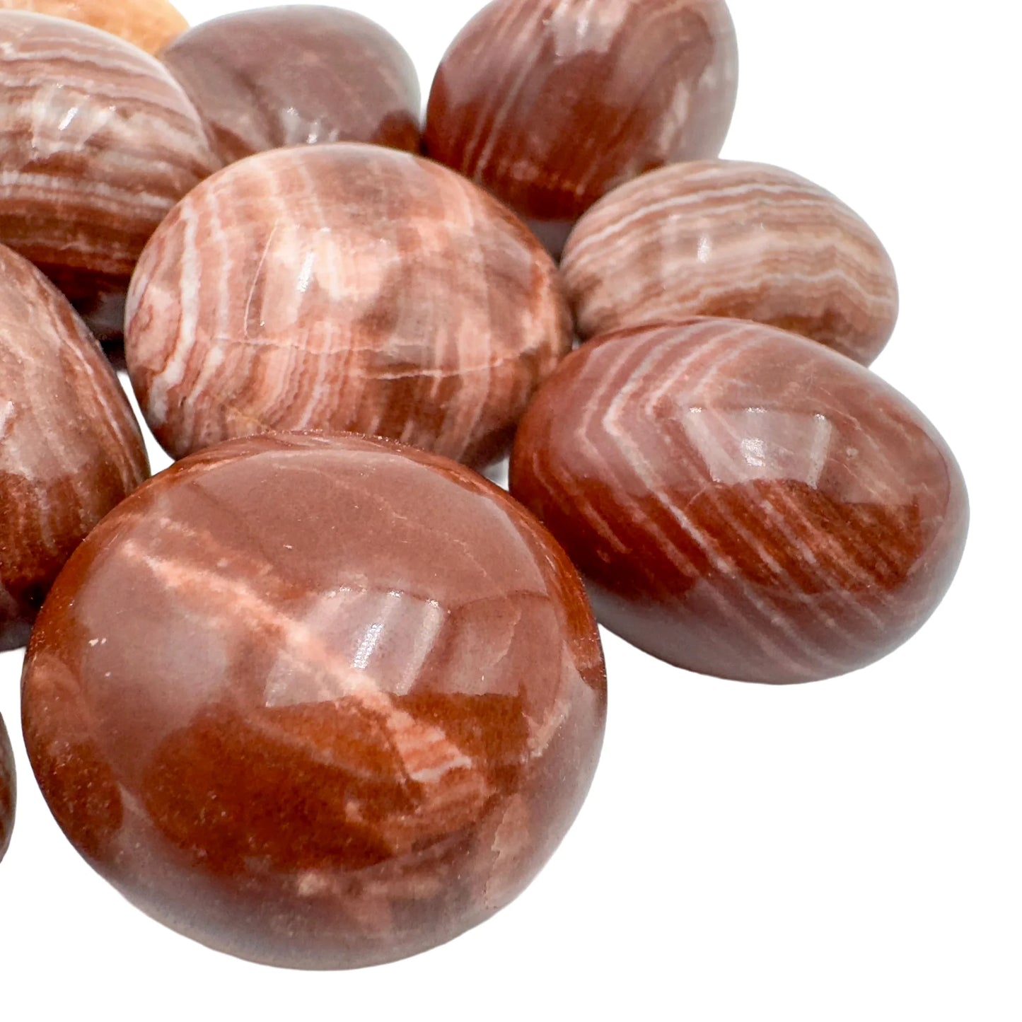 Side-on view of Grade AAA Red Aragonite tumbled stone, showing natural texture, for Energy.