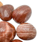 Looking down on Red Aragonite tumbled stone, sourced from Junín, Peru, showing translucent edges.