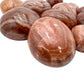 Size comparison with a single Red Aragonite tumbled stone Peru-sourced.