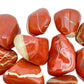 Hand-held view of a Red Jasper tumbled stone drawn on for Grounding, sourced from Northern Cape, South Africa.
