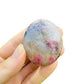 Side profile of pink Rhodonite palm stone, Madagascar-sourced, showing matte finish.