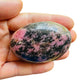 Resting display of Rhodonite palm stone, captured in soft, even lighting.