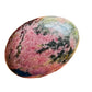 Detail shot of Grade AA Rhodonite palm stone under natural light
