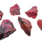 Three-quarter view of Rhodonite raw crystal, set against a soft neutral surface.