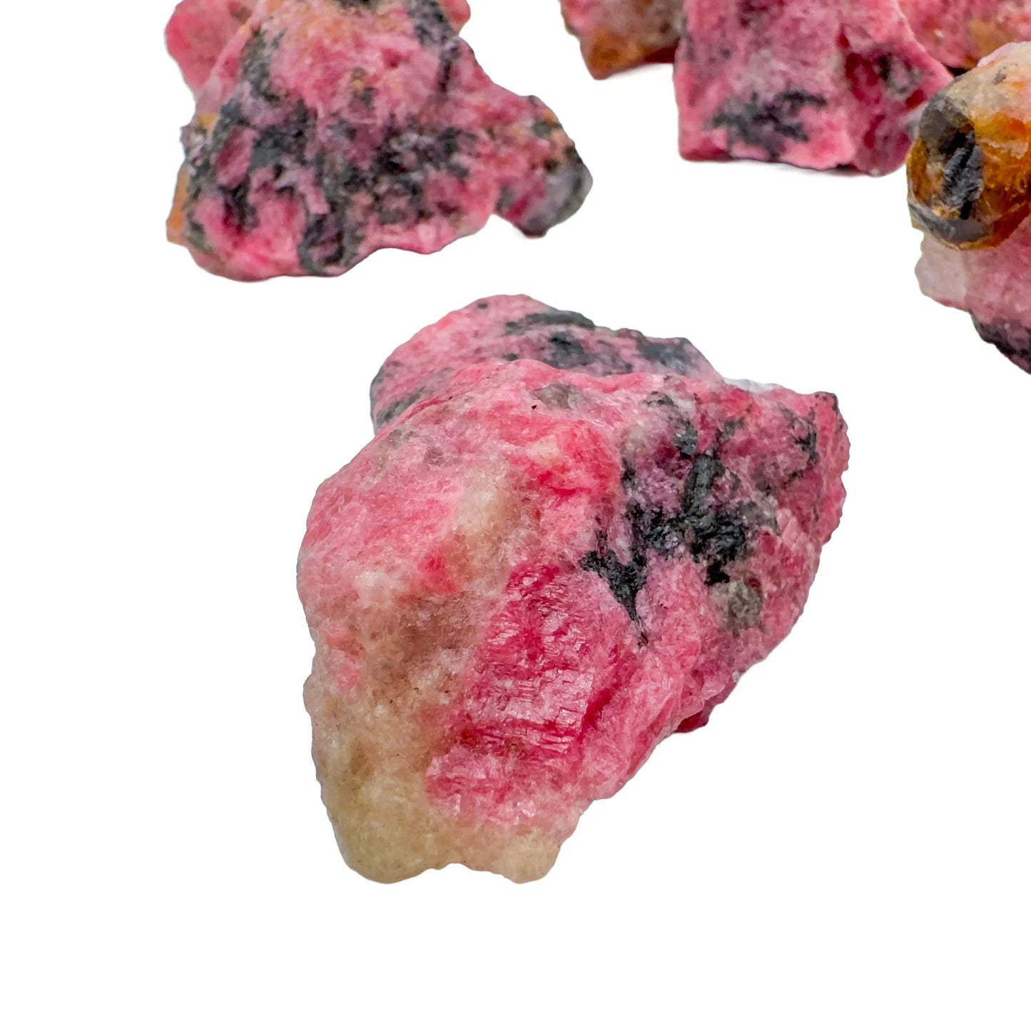 Sideways view of Rhodonite raw stone, showing natural form, hand-selected from Masvingo, Zimbabwe.