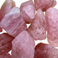 Hand-scale shot of a Rose Quartz raw stone held against natural backdrop.