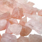Hand holding small rose quartz raw stones 5-10 grams Brazil scale reference
