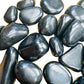 Side-on view of Shungite tumbled stone, to support Protection, showing soft luster.