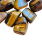 Detail shot of Grade A Tiger Eye tumbled stone under natural light