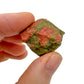 Holding an Unakite raw crystal, with hand-sized presence.