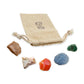 Cancer Crystal Kit: peach moonstone, pink opal, banded carnelian, blue calcite and emerald, arranged with the reusable cotton bag they come in, on white