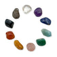 Ten tumbled chakra stones laid in a circle on white: clear quartz, amethyst, sodalite, aquamarine, green aventurine, rose quartz, golden healer, carnelian, black tourmaline and smoky quartz