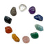 Ten tumbled chakra stones laid in a circle on white: clear quartz, amethyst, sodalite, aquamarine, green aventurine, rose quartz, golden healer, carnelian, black tourmaline and smoky quartz