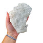 The Clear Quartz cluster specimen held in one hand, showing its 6 inch span