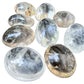 Clear Quartz palm stones arranged to show the range from medium to extra large