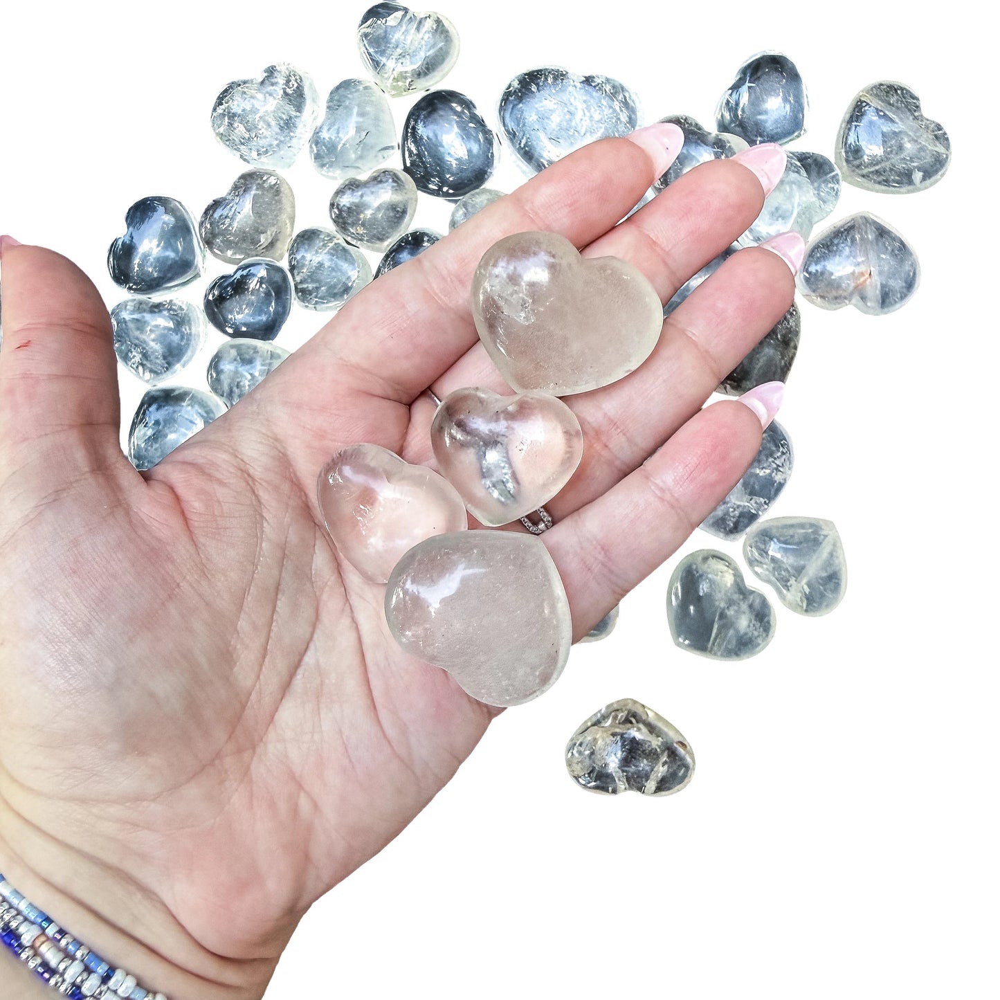 A Clear Quartz polished heart held in an open palm for scale